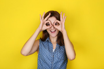 Young woman in stylish clothing on yellow background
