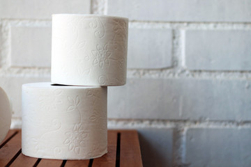 White toilet paper rolls and other home related objects against a white wall. Copy space.