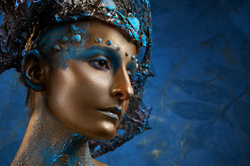  a girl in gold blue creative makeup and headdress