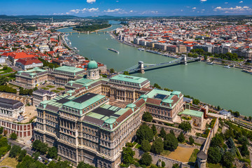 Fototapeta premium Budapest, Hungary - Aerial skyline view of Buda Castle Royal Palace on a bright summer day with Szechenyi Chain Bridge, River Danube and Parliament of Hungary at background taken with a drone