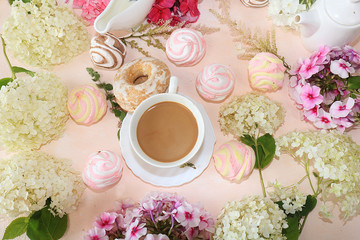 Flowers, muffins and a cup of coffee on the desktop, top view, flat lay. Break at work in the office in comfortable conditions, the comfort of our home
