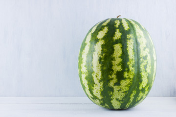 Watermelon on natural white background. Whole watermelon on wooden background. Healthy food for vegan. Copy space