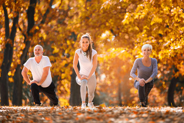 Senior man and woman and young female instructor  workout on fresh air. Outdoor activities, healthy lifestyle, strong bodies, fit figures. Stylish, modern sportswear. Different generations