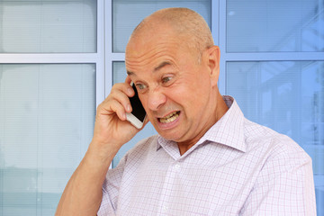 middle-aged man swears on the phone, grimace, concept, close-up, copy space