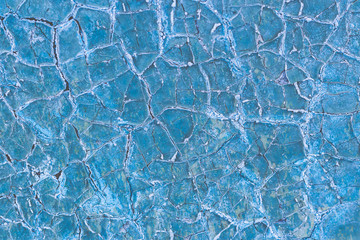 Texture of a dry cracked blue paint on a metal surface. Cracks on the iron wall. Abstract background.