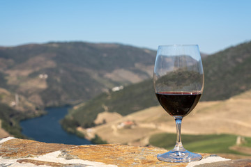Glass of red wine or port for tasting above the hillsides of the Douro valley in Portugal