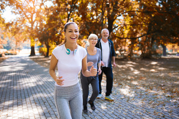 Senior man and woman and young female instructor  workout on fresh air. Outdoor activities, healthy lifestyle, strong bodies, fit figures. Stylish, modern sportswear.