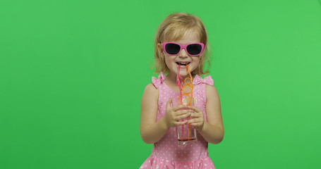 Child in pink swimsuit drinks juice cocktail with drinking straw. Chroma Key