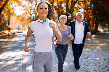 Senior man and woman and young female instructor  workout on fresh air. Outdoor activities, healthy...