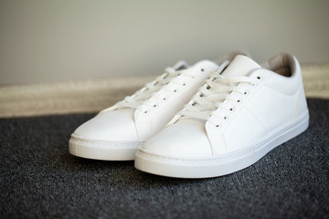 Fototapeta na wymiar Pair of new stylish white sneakers on floor at home.