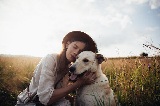 Beautiful young woman relaxed and carefree enjoying a summer sunset with her lovely dog