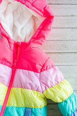 rainbow toddlers puffer jacket, wooden background