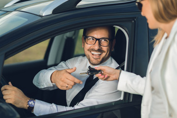 Happy businessman taking the car keys from unrecognizable person