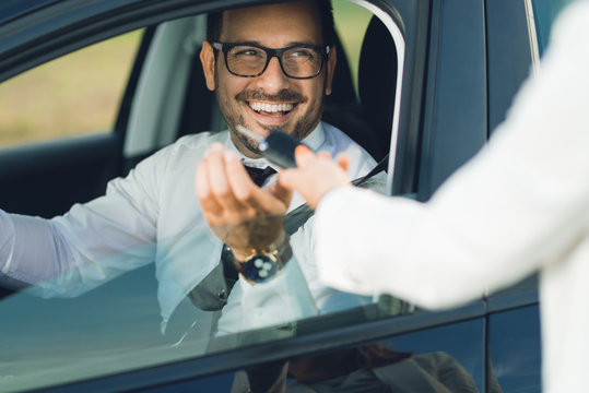 Happy businessman taking the car keys from unrecognizable person