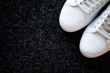 Pair of new stylish white sneakers on floor at home.