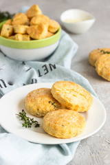 Savory scones or cookies with cheese and thyme on a white ceramic plate. Light grey concrete background. 