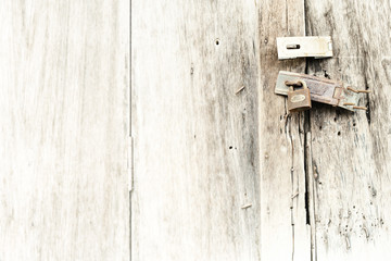 Old and rusty padlock on wooden door.