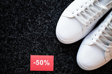 Pair of new stylish white sneakers with discount on gray background.