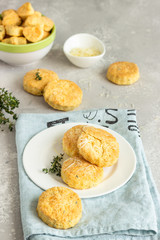Savory scones or cookies with cheese and thyme on a white ceramic plate. Light grey concrete background. 