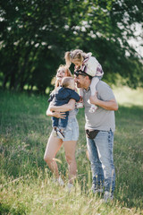 Happy family posing in a green park on sunny day.