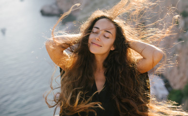 Happy woman with long hair posing on a top of the mountain.