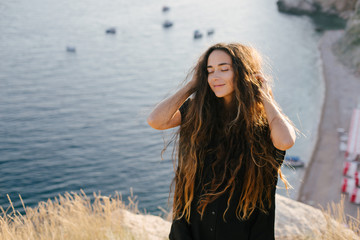 Happy woman with long hair posing on a top of the mountain.