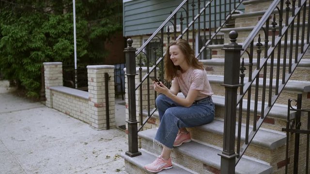 Surprised Woman Watching Screen Of Mobile Phone And Laughing On The Stairs