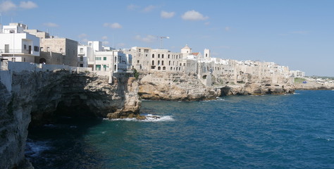 Fototapeta na wymiar Polignano, seafront : Medieval touristic city in Apulia, Italy built on a rocky ridge overlooking the Adriatic Sea and famous for the singer Modugno and for the event Red Bull cliff diving.