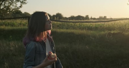 Young happy girl walking and eating red apple