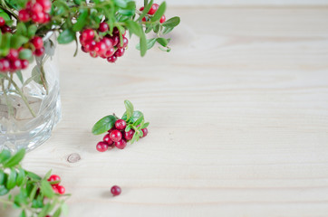bouquet of twigs with red ripe lingonberries in glass on wooden background. traditional vegetation of North America, Scandinavia, Sweden, Baltic, Russia. Cowberry, foxberry. copy space, mock up, next