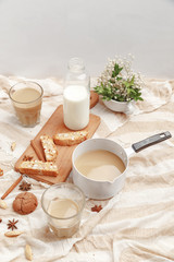 Coffee with milk, cookies, cinnamon and fruits on the tablecloth.