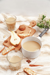Coffee with milk, cookies, cinnamon and fruits on the tablecloth.