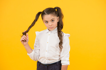Curly hair ponytails for back to school. Adorable small girl twisting hair around her finger on...