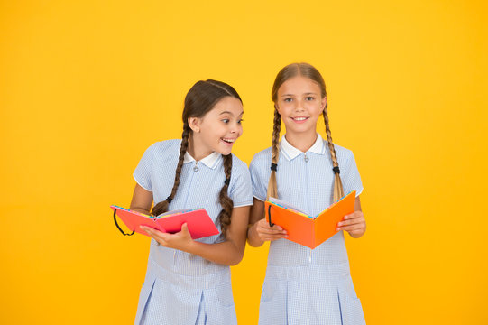 Reading and retelling. Small children holding books yellow background. Sincere interest. Little girls with encyclopedia or childrens books. School library. Educational books for school. Reading books