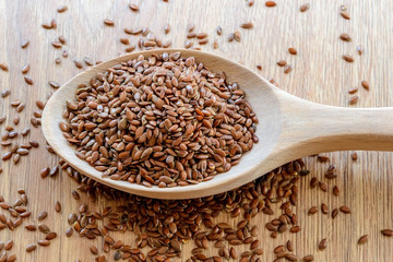 Wooden spoon of whole flax seeds on a wooden table. Healthy food for lower cholesterol and...
