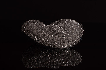 One whole iron cleaning kitchen sponge isolated on black glass
