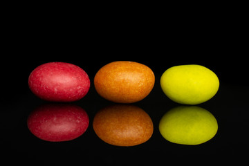 Group of three whole sugared nut dragee isolated on black glass