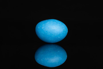 One whole blue sugared nut dragee isolated on black glass
