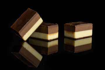 Group of three whole mellow two coloured nougat piece isolated on black glass