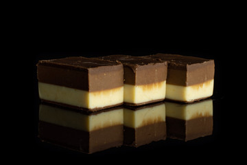 Group of three whole mellow two coloured nougat piece in row isolated on black glass