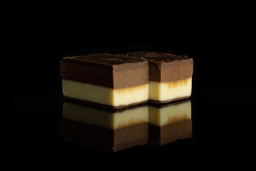 Group of two whole mellow two coloured nougat piece in row isolated on black glass