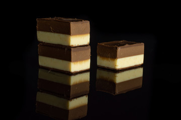 Group of three whole sweet mellow two coloured nougat piece isolated on black glass