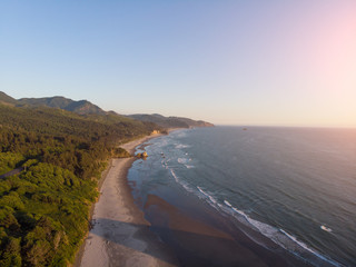 embankment of the ocean with sand and a road in the forest, at sunset shot from a high point, frame...