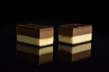 Group of two whole sweet mellow two coloured nougat piece isolated on black glass