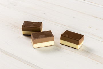 Group of three whole mellow two coloured nougat piece on white wood