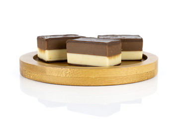Group of three whole sweet mellow two coloured nougat piece on bamboo plate isolated on white background