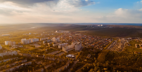 Shot of a beautiful city located at the edge of a forest, and a cloudy blue sky, during sunrise.