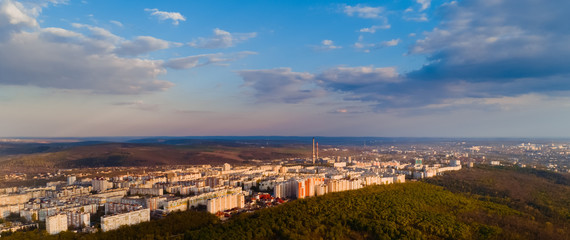 Shot of a beautiful city located at the edge of a forest, and a blue sky, during a majestic sunrise.