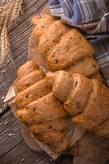 Freshly baked croissants on wooden boards, with wheat eart. Free space for text.