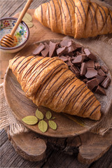 Freshly baked croissants with chocolate and honey on wooden boards. Free space for text.